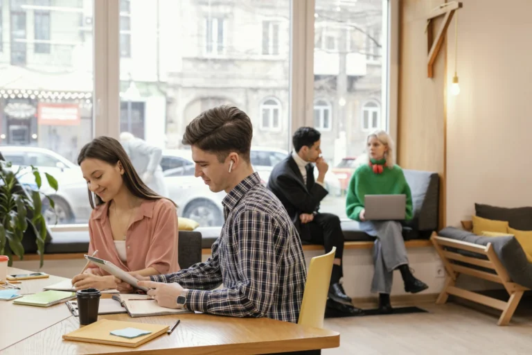 Professionals working together in a modern office with a Paris street visible outside, illustrating professional French in the workplace.
